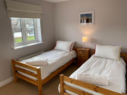 two twin beds in a room with a window at Malmesbury 3 Bedroom Town House in Malmesbury