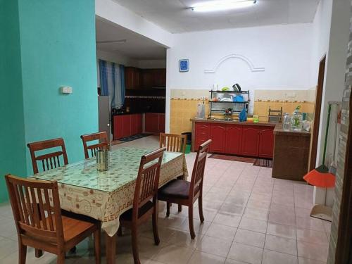 a dining room with a table and chairs and a kitchen at AlFateh Homestay Kepala Batas in Kepala Batas