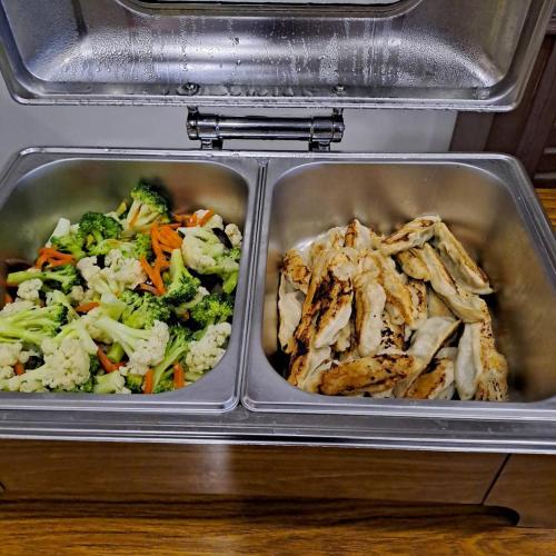 two metal trays of food in a refrigerator at Tzu Chi Hotel in Pingtung City