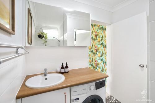 a bathroom with a sink and a washing machine at Tropicana Pineapple in Cairns North