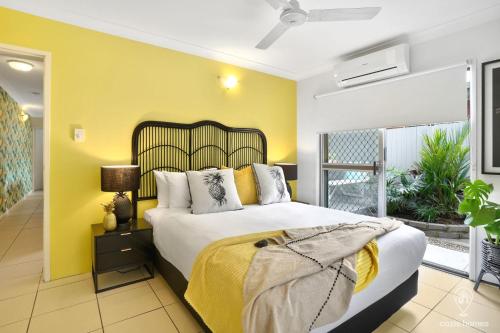 a bedroom with a large bed and a yellow wall at Tropicana Pineapple in Cairns North