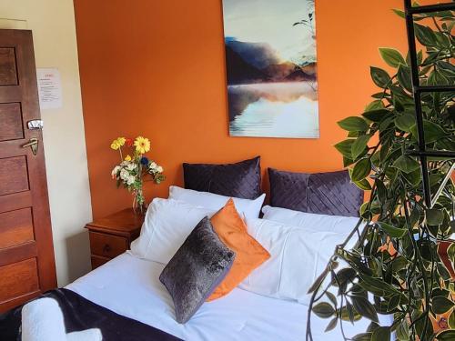 1 dormitorio con cama blanca y pared de color naranja en The Garston Lodge en Garston