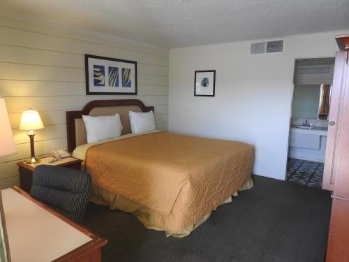 a hotel room with a bed and a table and lamp at Economy Inn in Socorro
