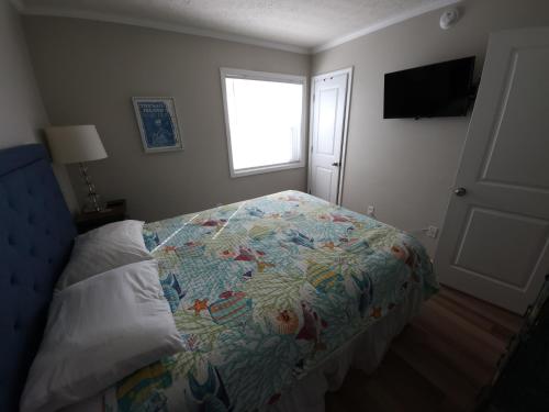 ein Schlafzimmer mit einem Bett mit einer bunten Decke und einem Fenster in der Unterkunft Steps To The Ocean! 152 in North Topsail Beach