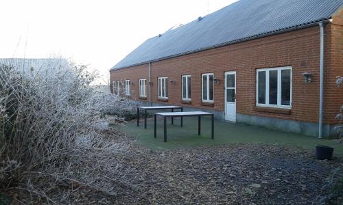 two picnic tables in front of a brick building at Agervig Bed & Breakfast in Næsbjerg