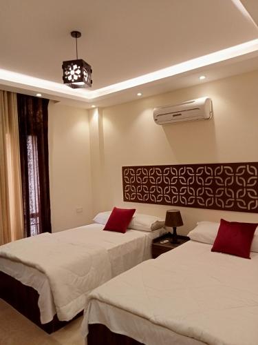 ein Hotelzimmer mit 2 Betten und roten Kissen in der Unterkunft Relax Guest House in Madinat as-Sadis min Uktubar