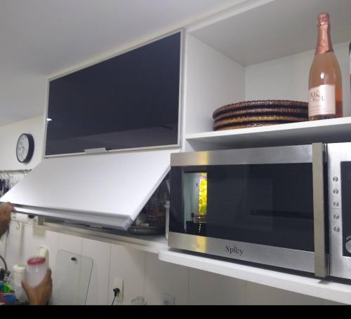 a microwave on a counter with a bottle of wine at Quinta das Lagoas Residence in Itacimirim