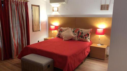 a bedroom with a red bed with two lamps at Vila sol in Armação de Pêra