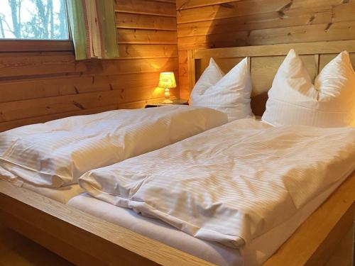 a bed with white sheets and pillows in a room at Cozy holiday home on a horse farm in the Lüneburg Heath in Eschede