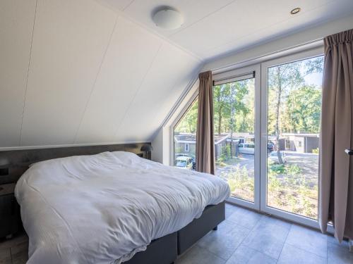1 dormitorio con cama y ventana grande en Group accommodation with infrared sauna, in a holiday park in nature, en Hoenderloo