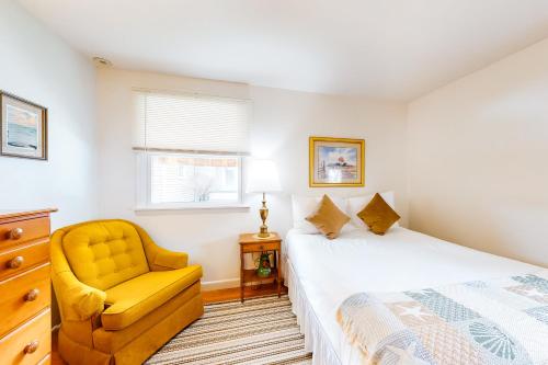 a bedroom with a bed and a yellow chair at Tideview in Owls Head