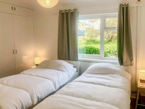 two beds in a room with a window at Courtfield Bungalow in Totnes