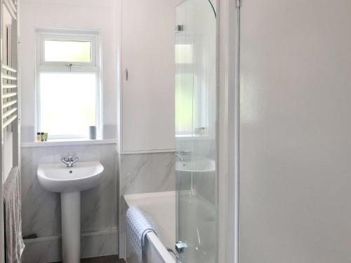 a white bathroom with a sink and a shower at Courtfield Bungalow in Totnes