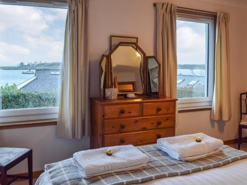 a bedroom with a dresser and a mirror and a bed at Brandystone Cottage in Oban