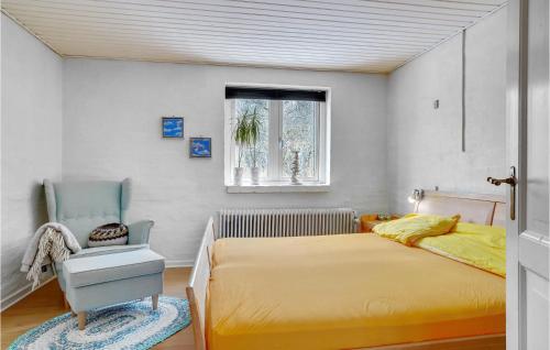 a bedroom with a yellow bed and a blue chair at Cozy Home In Vestervig With Kitchen in Vestervig