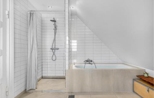 e bagno con vasca e piastrelle bianche. di Beautiful Home In Dyssegrd With Kitchen a Søborg