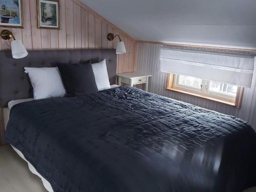 Schlafzimmer mit einem großen schwarzen Bett und einem Fenster in der Unterkunft Holiday home GRISSLEHAMN XII in Grisslehamn