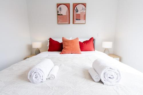 Un dormitorio con una cama blanca con toallas. en Sunny townhouse Central city 2 bedroom, en Christchurch