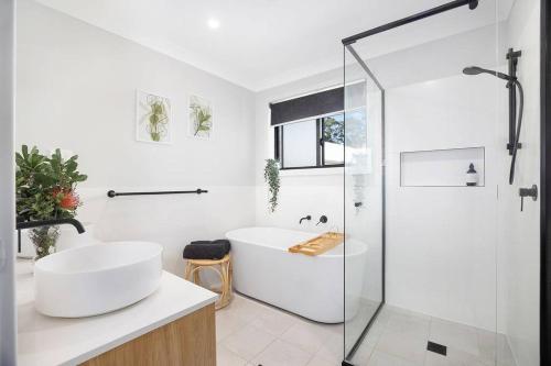 un bagno bianco con vasca e doccia in vetro di Poolside @ Brookwater a Mollymook