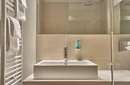 a bathroom with a white sink and a mirror at Hotel Conti Duisburg - Partner of SORAT Hotels in Duisburg