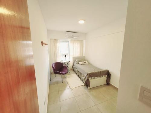 a bedroom with a bed and a chair in a room at Dpto. nuevo, luminoso, 3 dormitorios, pleno centro in Rosario