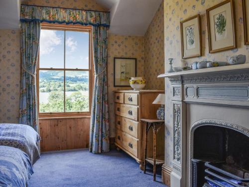 a bedroom with a fireplace and a window at Sharrow Cottage in Watermillock