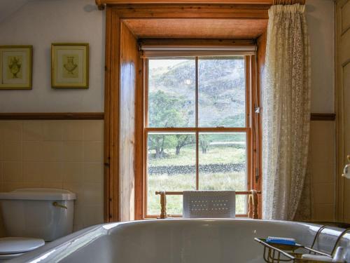 een badkamer met een bad en een raam bij Sharrow Cottage in Watermillock