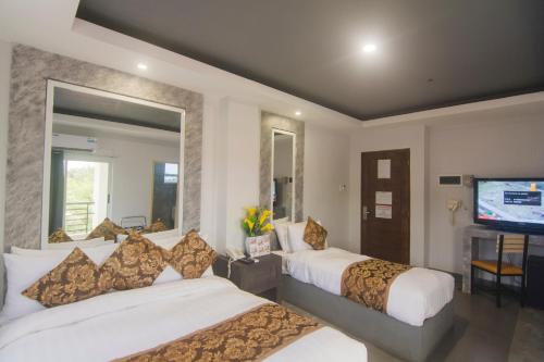 a hotel room with two beds and a flat screen tv at Hotel Carmelita in Tuguegarao City