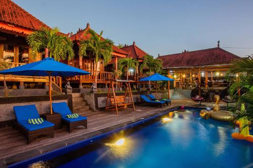 a resort with a swimming pool with blue chairs and umbrellas at Tatak Bunut Villa Ceningan in Nusa Lembongan