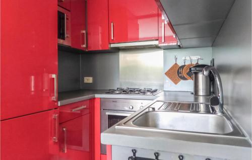 2 Bedroom Gorgeous Home In Rekem-lanaken في Bovenwezet: مطبخ مع خزائن حمراء ومغسلة حديد قابلة للصدأ