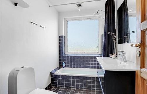 a bathroom with a tub and a sink and a window at Awesome Home In Allinge With 5 Bedrooms And Wifi in Allinge