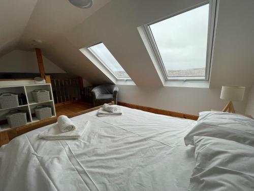 a bedroom with a white bed with two windows at Talla Hope in Portree