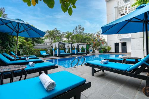 een zwembad met blauwe ligstoelen en parasols bij Hoi An Golden Holiday Hotel & Spa in Hội An