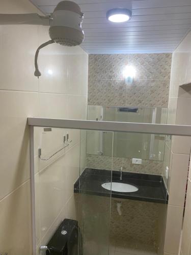 a bathroom with a sink and a mirror and a light at Cantinho da Dhéia 03 in Porto De Galinhas