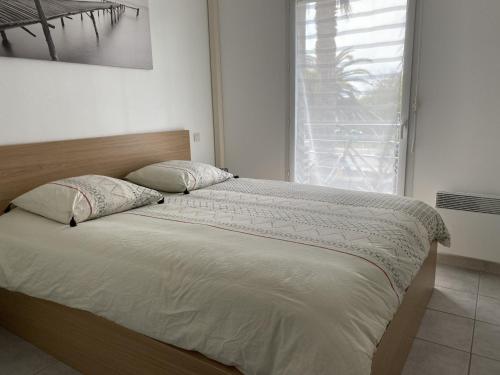 a bed in a bedroom with a large window at Appartement 2 pièces avec climatisation, parking, proche plage, commerces et activités - Classé 3 étoiles - FR-1-338-426 in Sète