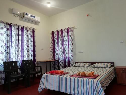 a bedroom with two beds and chairs and curtains at kannur west beach house in Kannur