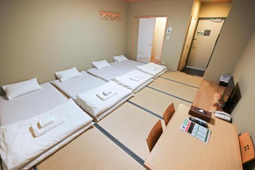 um pequeno quarto com 4 camas e uma televisão em Akihabara Nakagawa Inn em Tóquio