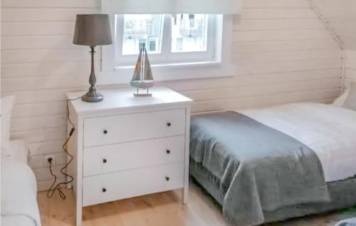 a white bedroom with a bed and a lamp on a dresser at Amazing Home In Miedzywodzie With Kitchen in Międzywodzie