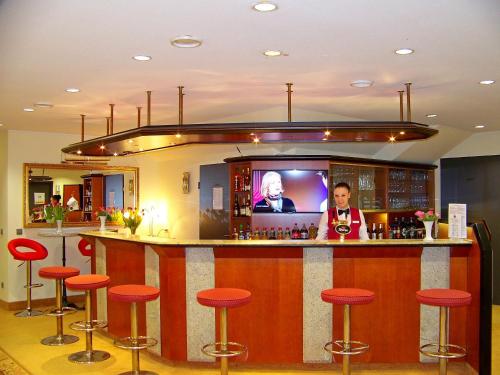 a bar with red stools and a flat screen tv at Hotel Amadeus ROYAL Berlin in Berlin