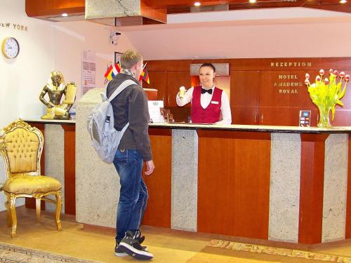 a man is standing at a bar with a cashier at Hotel Amadeus ROYAL Berlin in Berlin