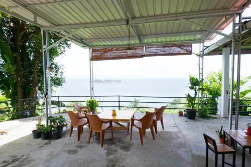 a table and chairs on a patio with a view of the ocean at The view padang, Amazing view, 8 mins Mentawai fast ferry, cold beer,close to restaurants in Padang