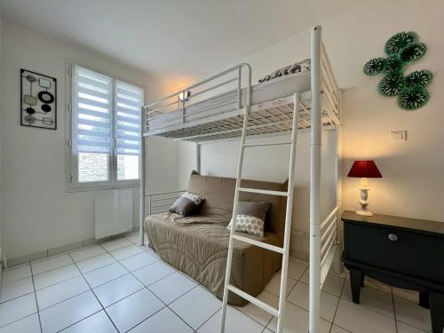 ein weißes Etagenbett in einem Zimmer mit einem Bett in der Unterkunft Maison cosy au centre de La Brée-les-Bains avec 4 couchages, proche plage, WiFi gratuit - FR-1-246A-219 in La Brée-les-Bains