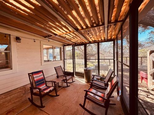 a screened in porch with rocking chairs and windows at 11th Street River House in Bandera