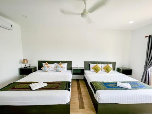 two beds in a room with white walls at HaiVen Farm Homestay in Phumĭ Khŭn Réam