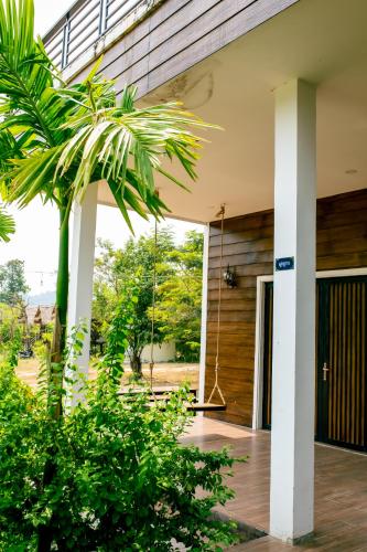 a porch with a swing and a palm tree at HaiVen Farm Homestay in Phumĭ Khŭn Réam