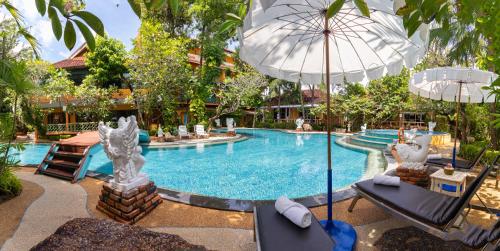 a swimming pool with two chairs and an umbrella at Aochalong Villa Resort & Spa - SHA Plus in Chalong 