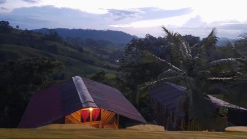 una pequeña casa con techo de paja y una palmera en glamping/cabañas Monaco en Santa Rosa de Cabal