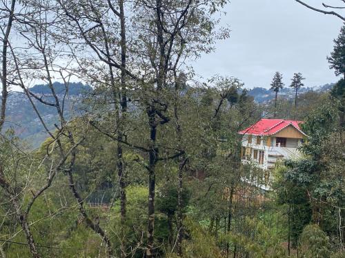 a house with a red roof in the forest at Bloomfield Farmhouse and Eco-Resort in Darjeeling