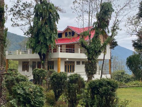 a large white house with a red roof at Bloomfield Farmhouse and Eco-Resort in Darjeeling