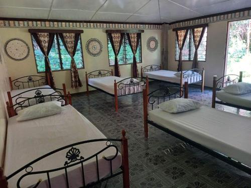 a room with four beds and windows at Wai Makare Homestay in Naviti Island